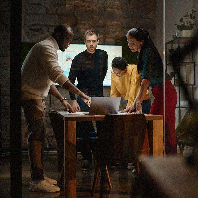 group of people looking at a laptop in office