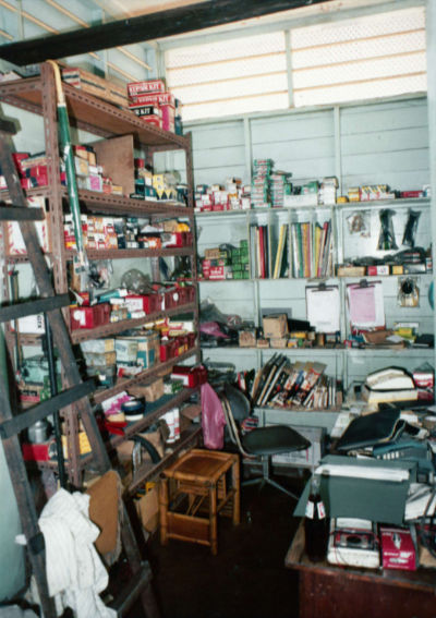 A cluttered storeroom in the office of Messrs Quek Hwa Heng Engineering, featuring shelves of random tools and supplies.