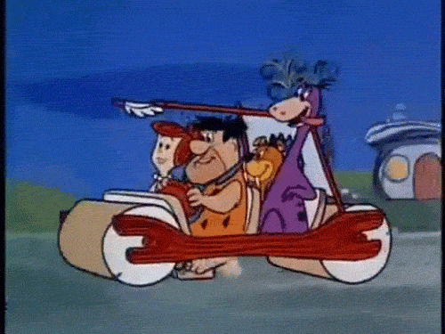 GIF of Fred Flintstone foot\-pedaling their prehistoric car