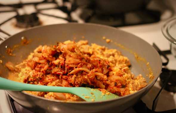 Eggs, protein, and kimchi starting to cook on stove