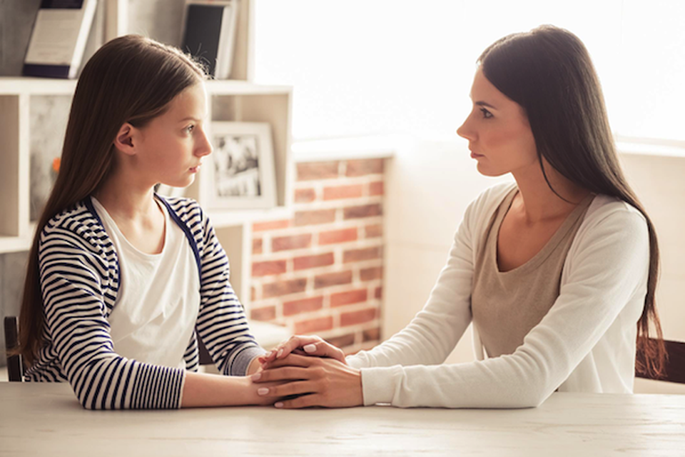 A woman and a girl looking at each other with serious face expressions