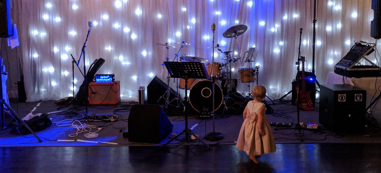 Equipment adorning an empty back-lit stage as a small child curiously approaches