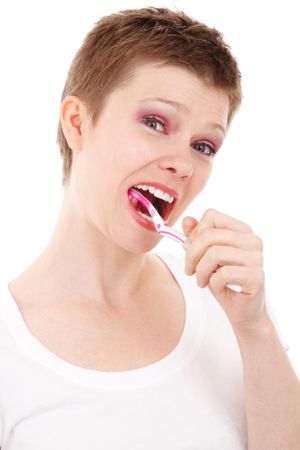A woman smiling while brushing her teeth