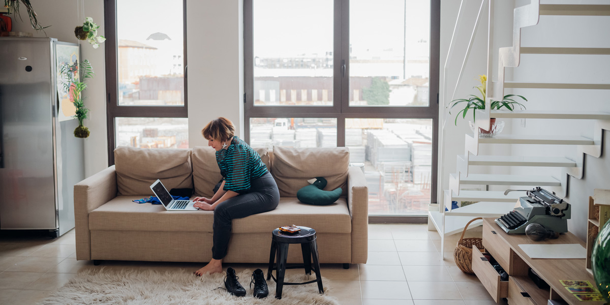 What are the best UI design certification programs? A woman sitting on a sofa in side profile, typing on a laptop keyboard