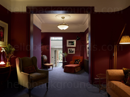 Dimly lit staggered living room decorated in deep red featuring two classic style arm chairs and orange sofa  Skype background