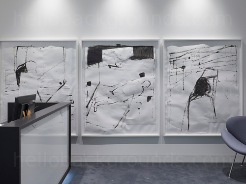 Modern shared workspace featuring wall mounted black and white modern art pieces behind reception desk and grey padded chair Microsoft Teams background