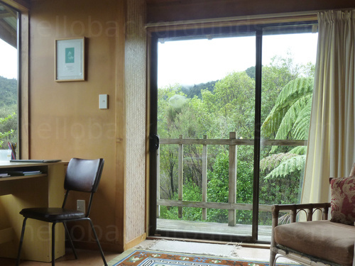 Naturally lit office with basic desk and office chair with large sliding door-windows holding tropical mountain views  Zoom background