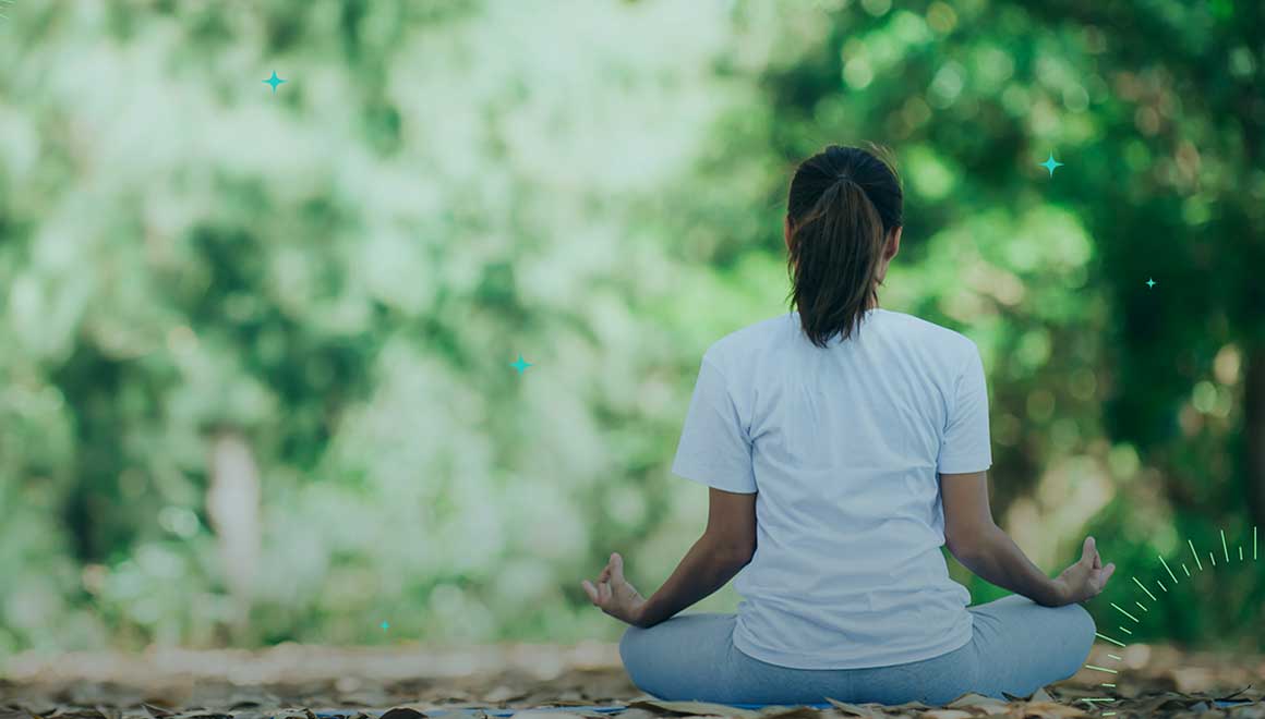 Image of a woman meditating in an outdoor setting.