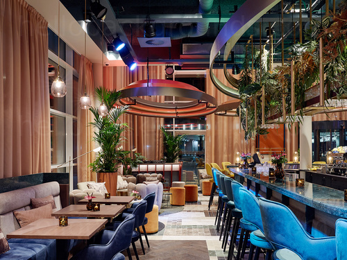 Bar interior featuring artistic decoration with blue marble bar and matching stools next to wooden table and padded seating Skype background
