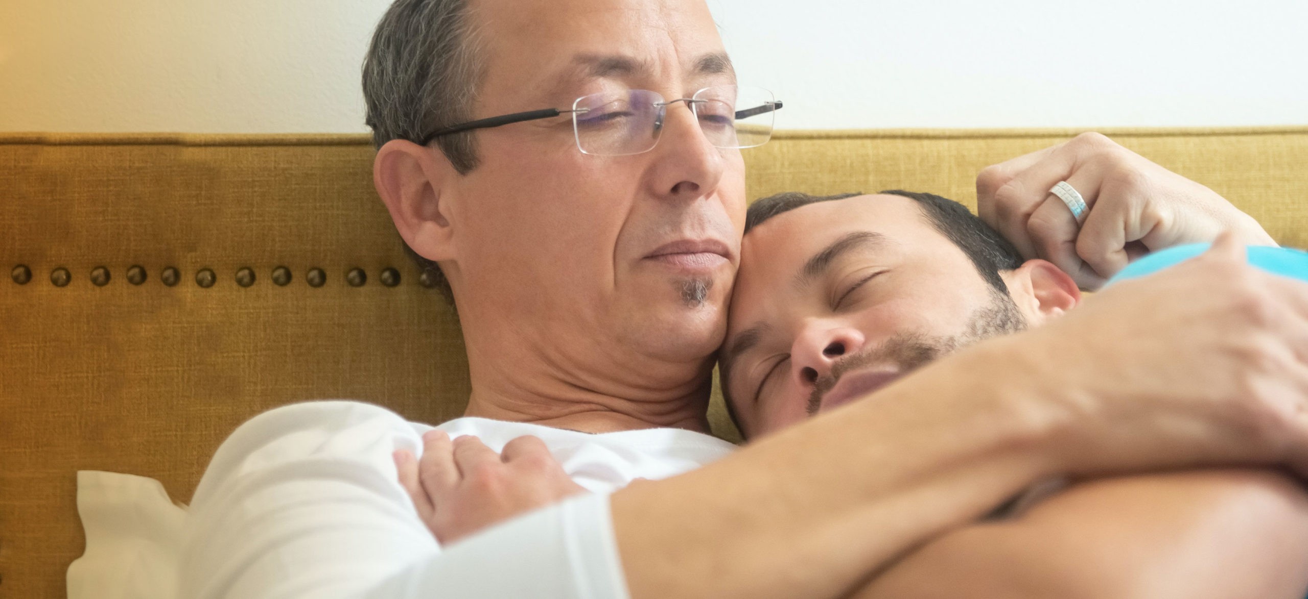 Two men embrace in a bed