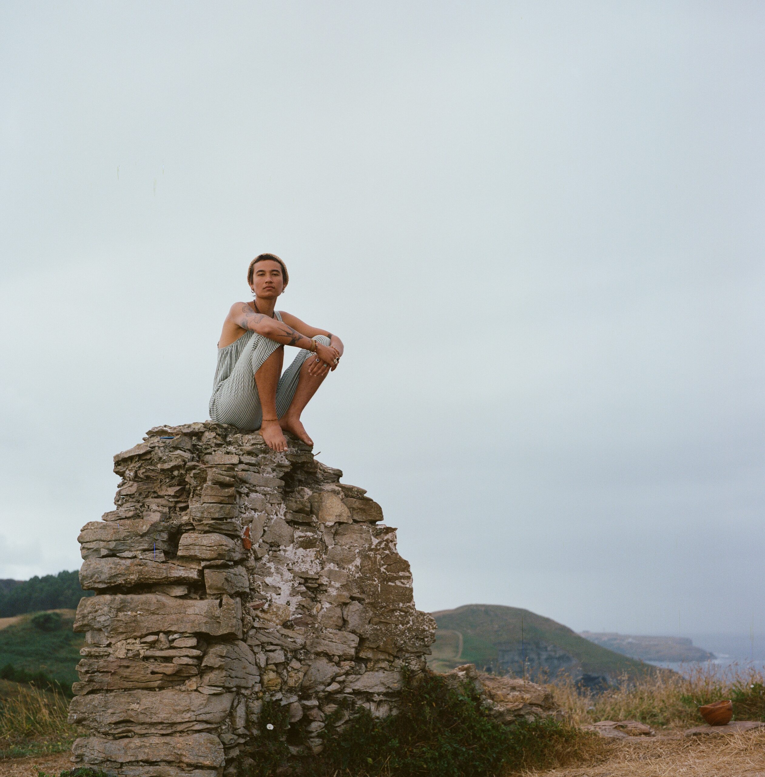 Person sitting on a stone on a cliff.