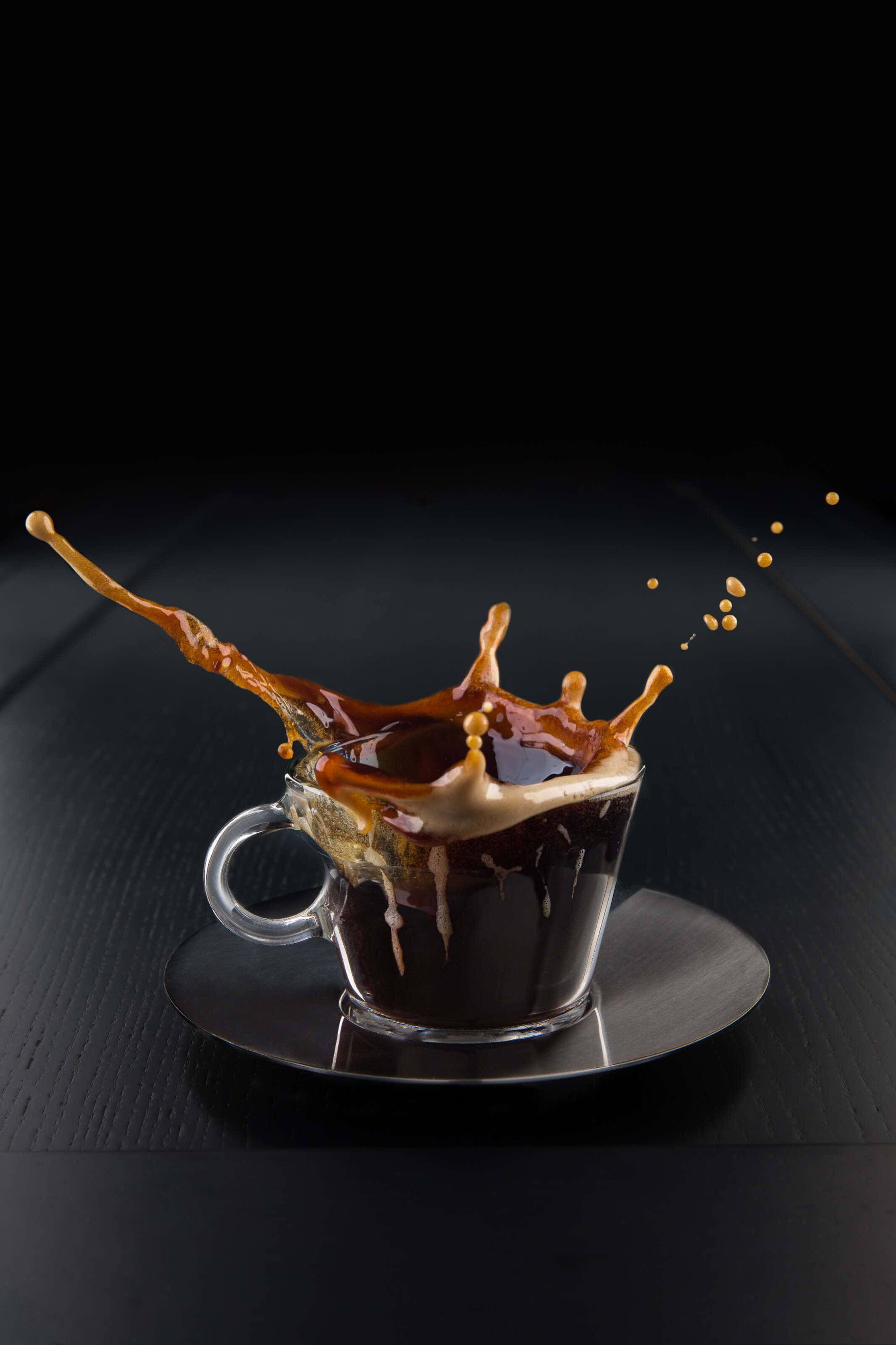 Nespresso coffee cup on a dark background with a splash coming out of it.