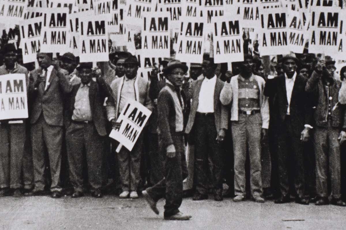 A black-and-white photo of a group of men holding picket signs that read ‘I AM A MAN.'