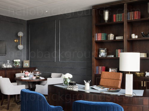 Executive style office with wooden furnishings featuring assorted seating and desk surfaces Google Meet background