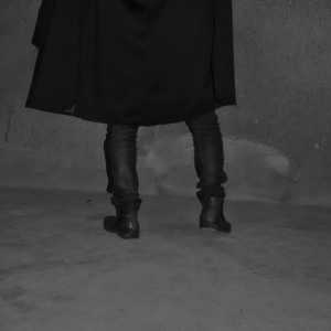 Sexy queer man in a black poncho. Avant garde fashion. Haute de couture. Tribal postapocaliptic fashion.