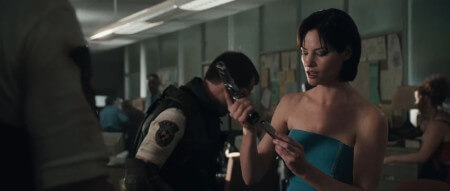 Jill Valentine reloads her pistol, as an unnamed STARS member digs around their desk
