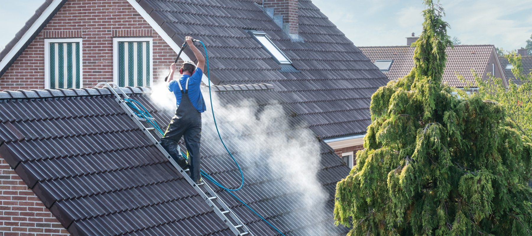 A Man on a Roof Doing a Pressure Wash Cleaning