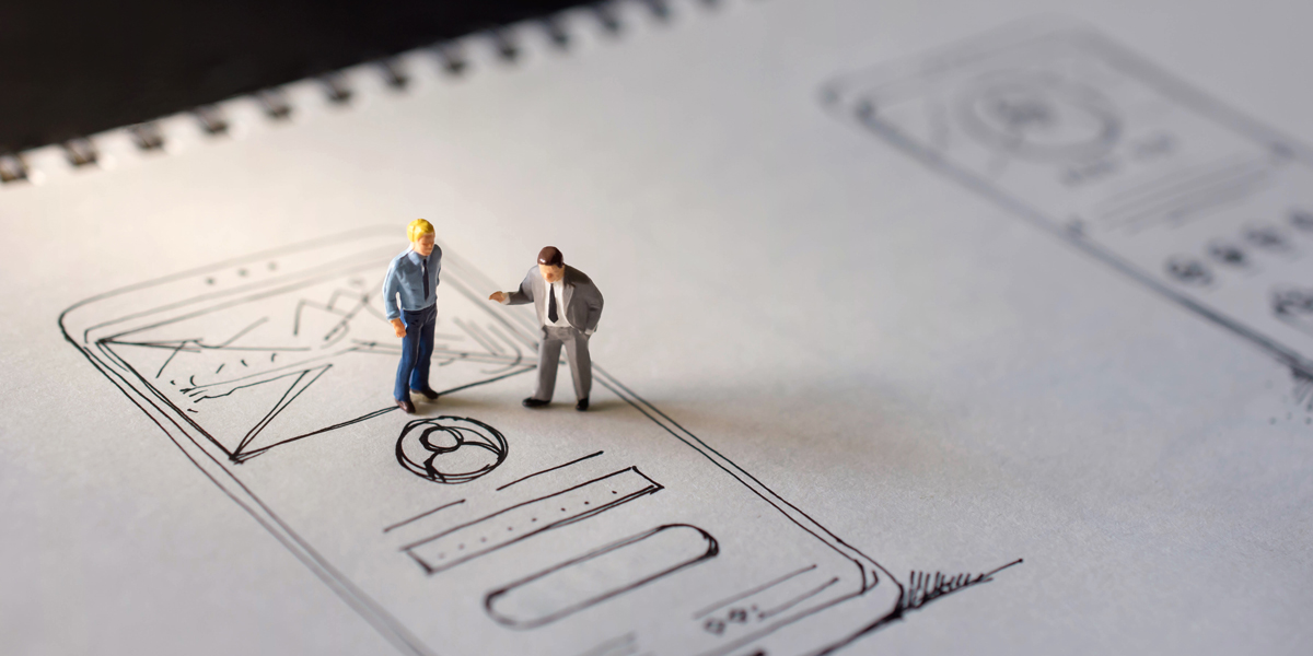 Two miniature figurines standing on top of a wireframe Two miniature figurines standing on top of a hand-drawn wireframe