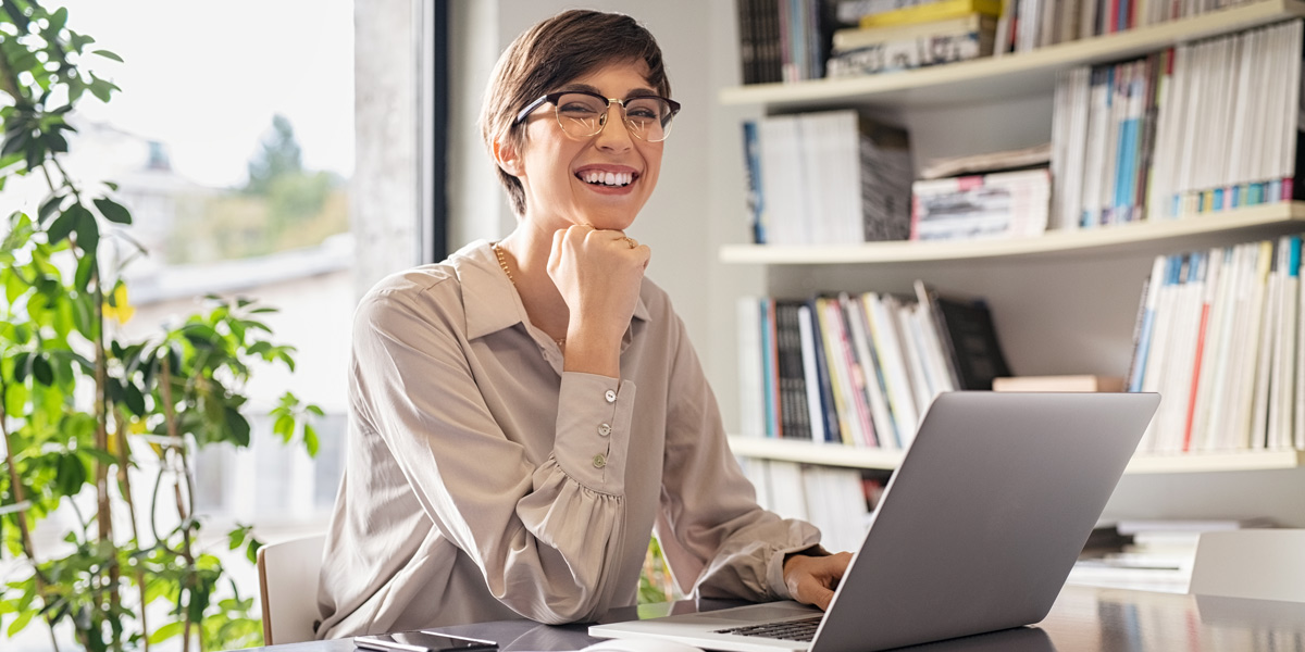 What is the typical data analyst career path? A woman sitting at a desk with her chin resting on her hand, smiling