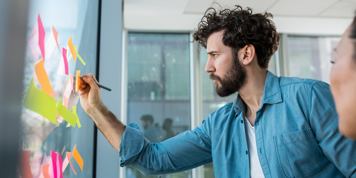 What is a Bildungsgutschein and how can you apply for one? A UX designer in side profile, placing sticky notes on a window
