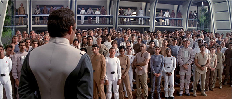 A scene from Star Trek where the entire crew is wearing blue, beige, or white jumpsuits