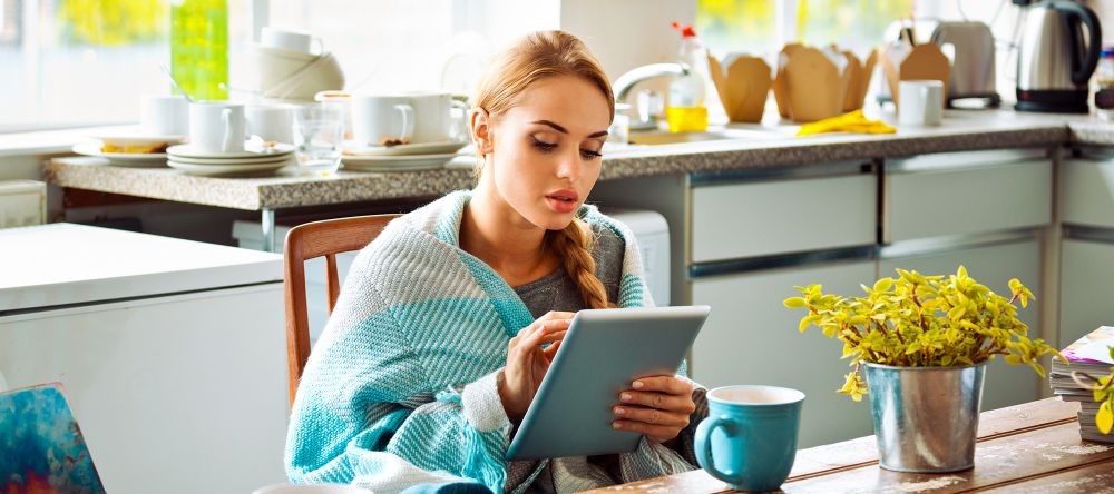 woman on a tablet bundled up in shawl on a couch