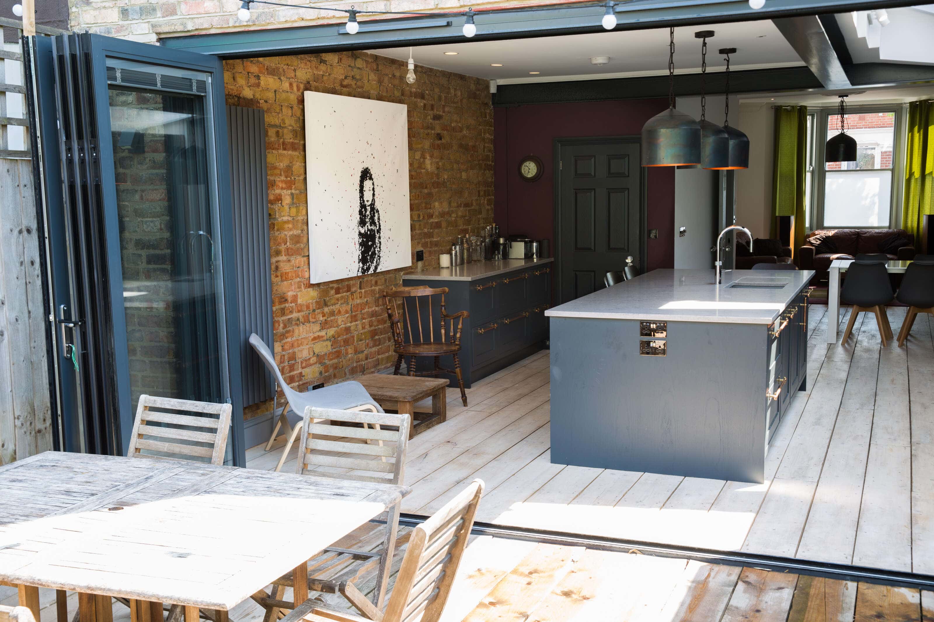 The view into the kitchen from the garden, looking through the wall to wall open door to the feature brick wall.