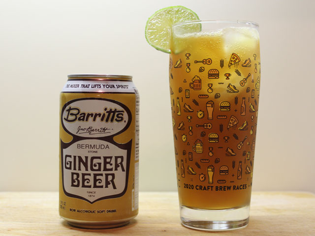 A 12oz can of Barritts Ginger Beer next to a poured and mix Dark and Stormy with lime wheel garnish