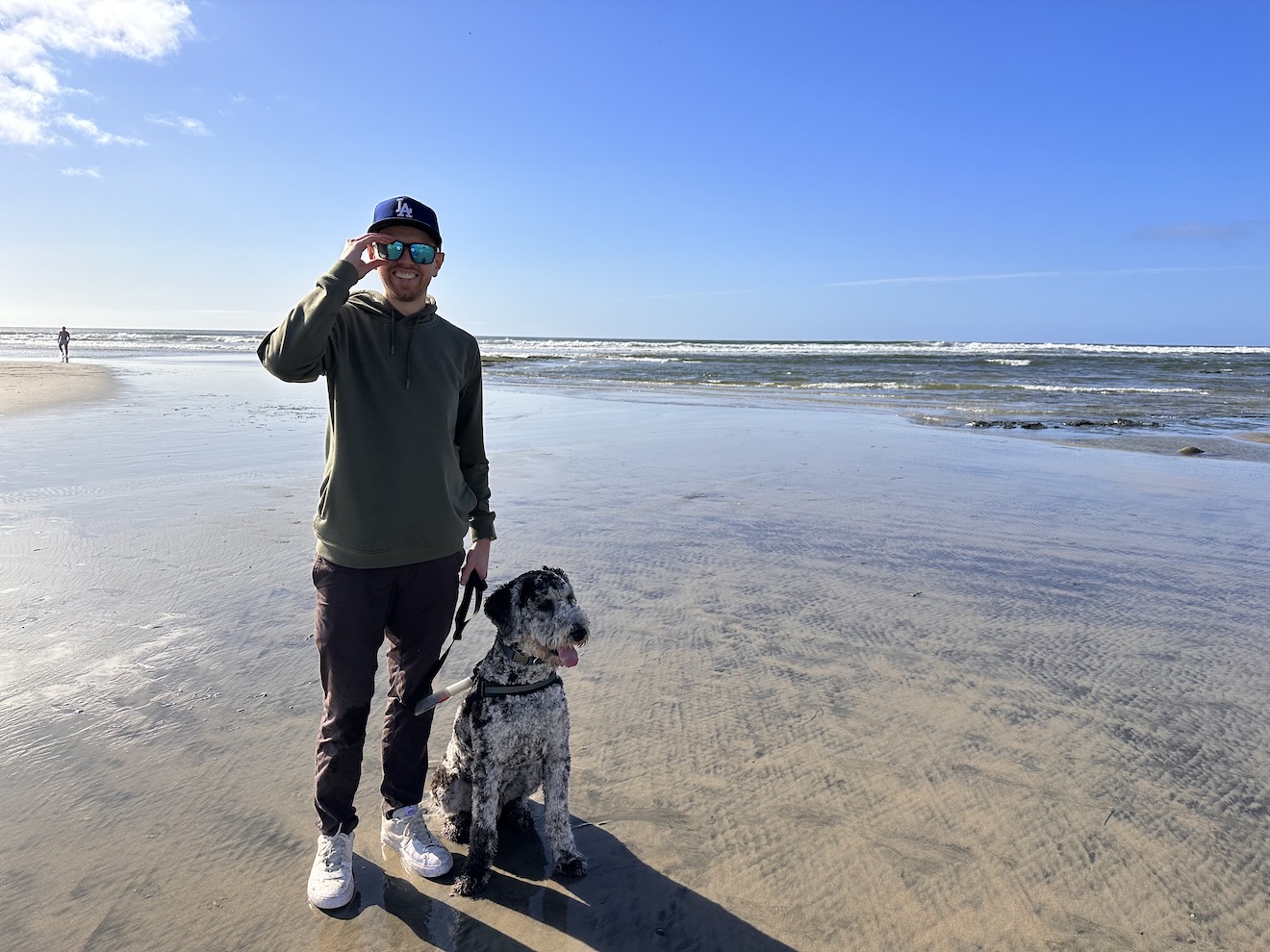 A photograph of my dog Dutch and I at Del Mar dog beach in southern California, looking out over the ocean with a mostly clear blue sky