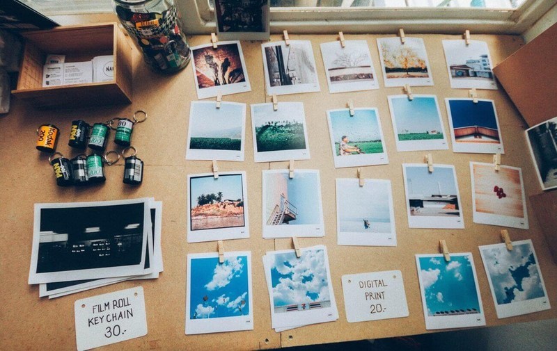 Várias fotos de polaroid presas por um prendedor e apoiadas em uma mesa.