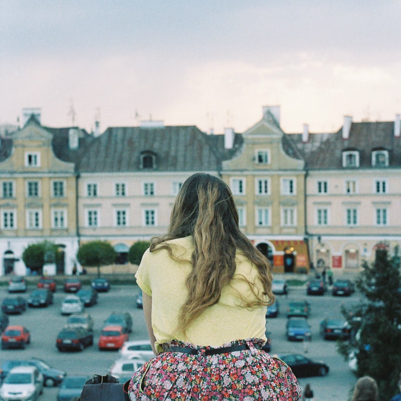 Leticia López Martínez sitting on her back in the open air with houses of the city of Lublin behind