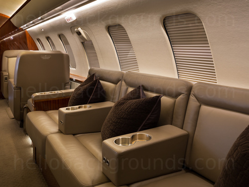 Private jet interior with bench style leather seats and plump cushions Zoom background