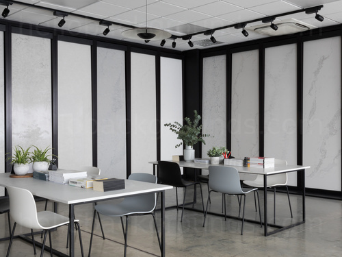 Contemporary shared workspace featuring white panel with black frame design walling behind white desks with grey chairs  Skype background
