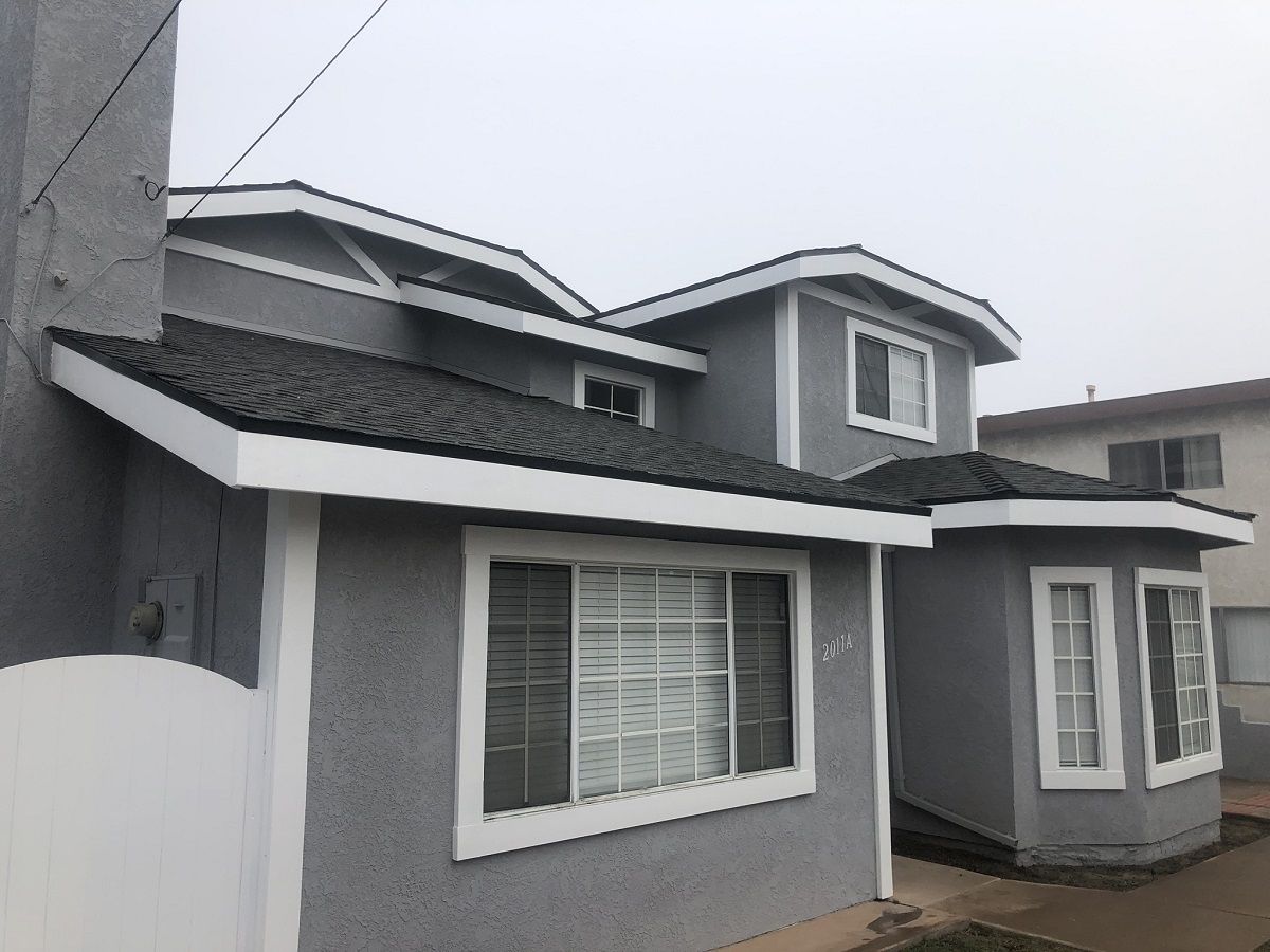 enlarged photo of grey stucco home with white painted trim