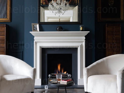 Minimal living room featuring a 2 white fabricated chairs against a white fireplace in a wall decorated in dark blue  Skype background