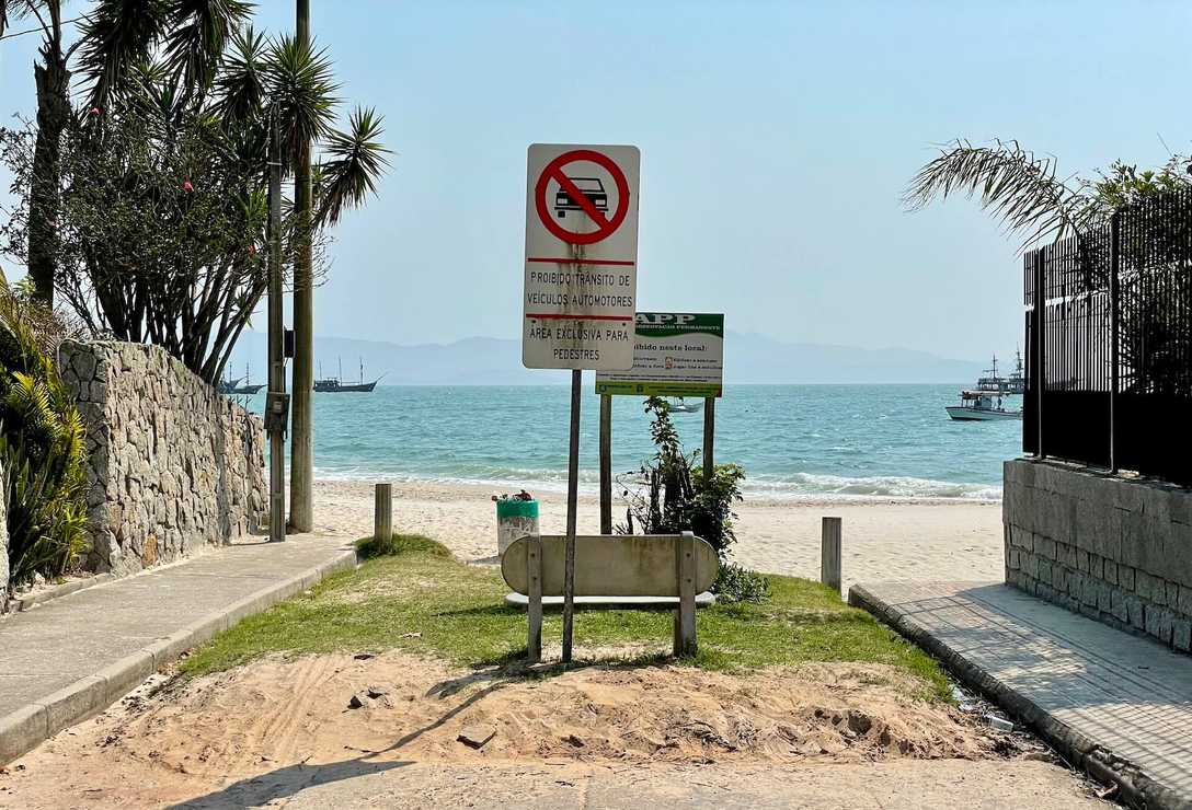 Entrada da praia com banco e mar ao fundo