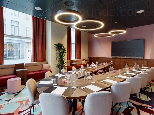Stylish boardroom with artistic flooring featuring V shaped table and circular rimmed lights Skype background