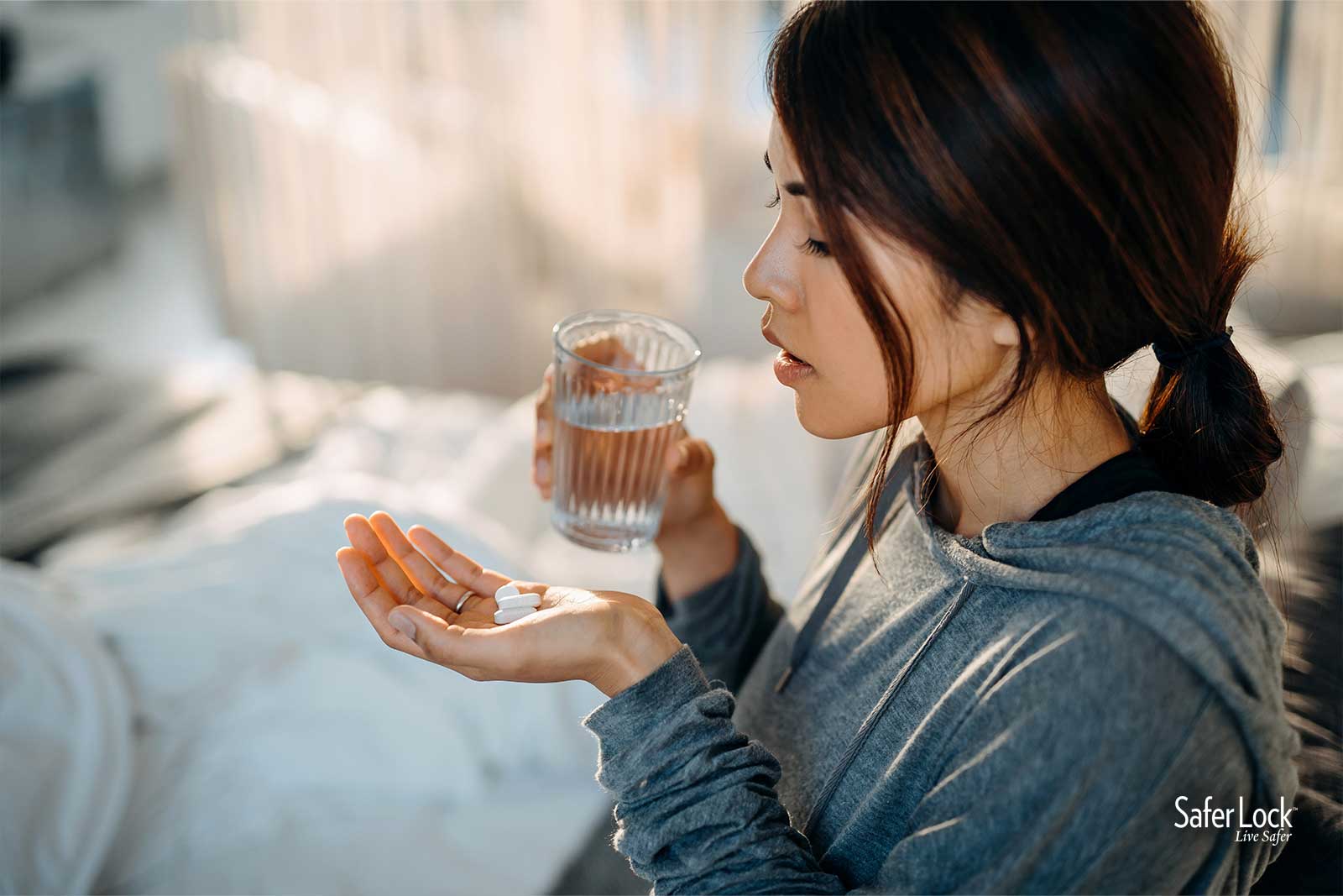 A young Latina woman with a glass of water and prescription pills. Learn how to use opioids safely at rxguardian.com.