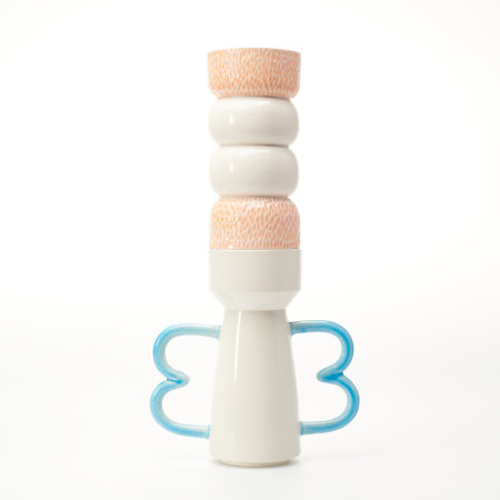 A totem consisting of two ceramic vessels stacked vertically, with two blue handles shaped like a capital B, and textured orange elements on the upper piece. The whole totem suggests a human form.