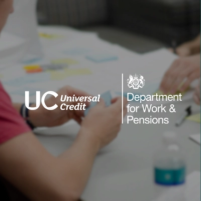 Universal Credit and Department of Work and Pensions logo on blured photo people working with postit notes