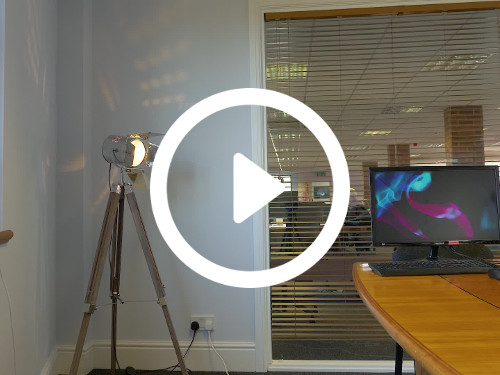 Compact private office with partial glass walls with blinds next to adjustable lamp and wooden desk with laptop computer Google Meet background