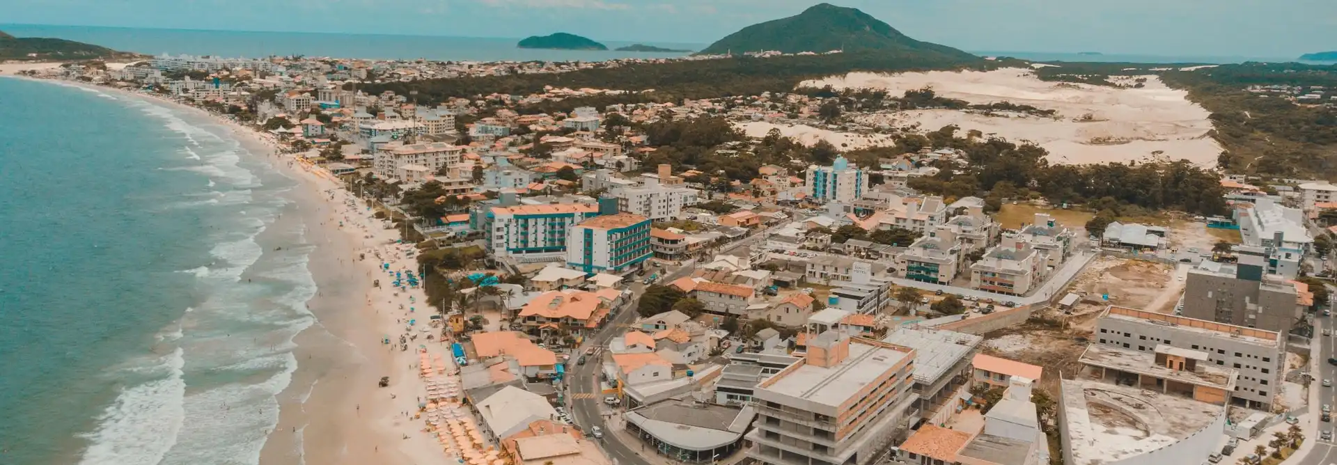 Foto aérea da para dos ingleses com vista dos apartamentos e dunas a direita e mar com faixa de area a esquerda.