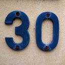 House number thirty in blue weathered letters screwed into sandstone.