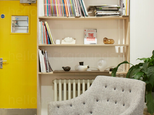 Homey private office simply decorated with wooden book shelf and grey padded chair Zoom background