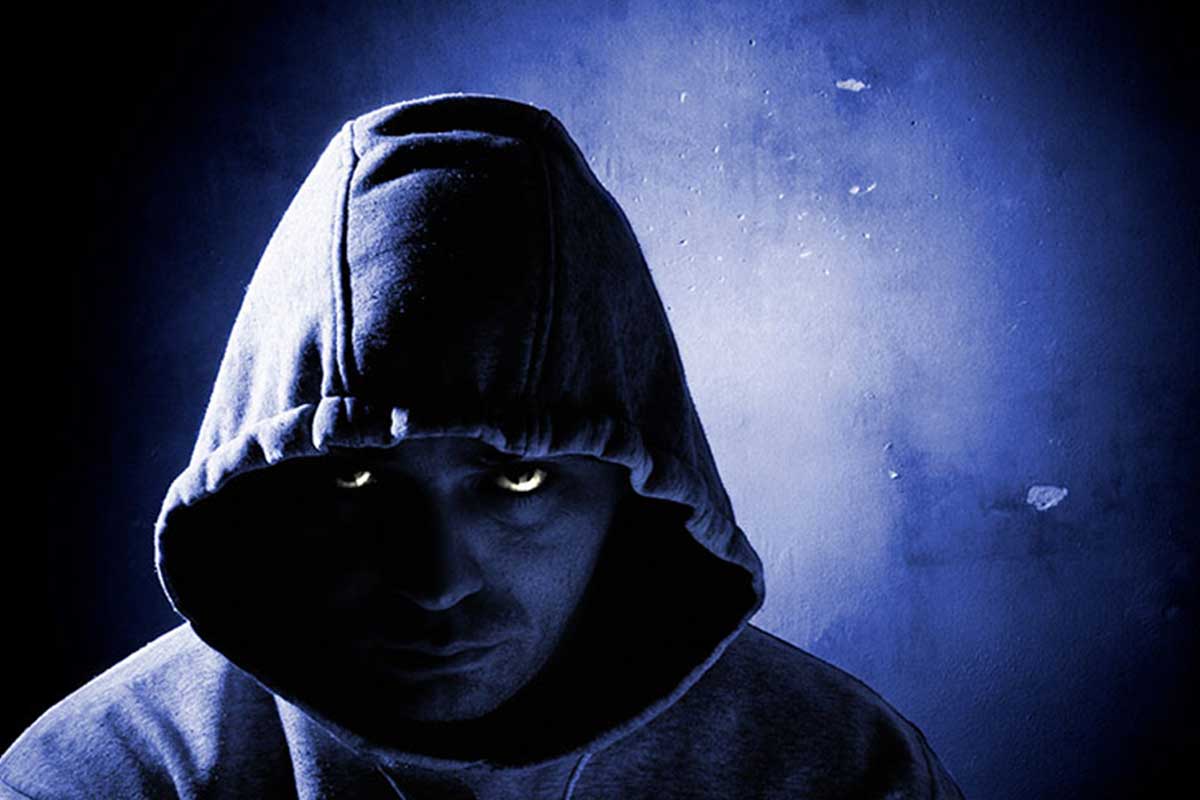 Dark image of a menacing hooded man.