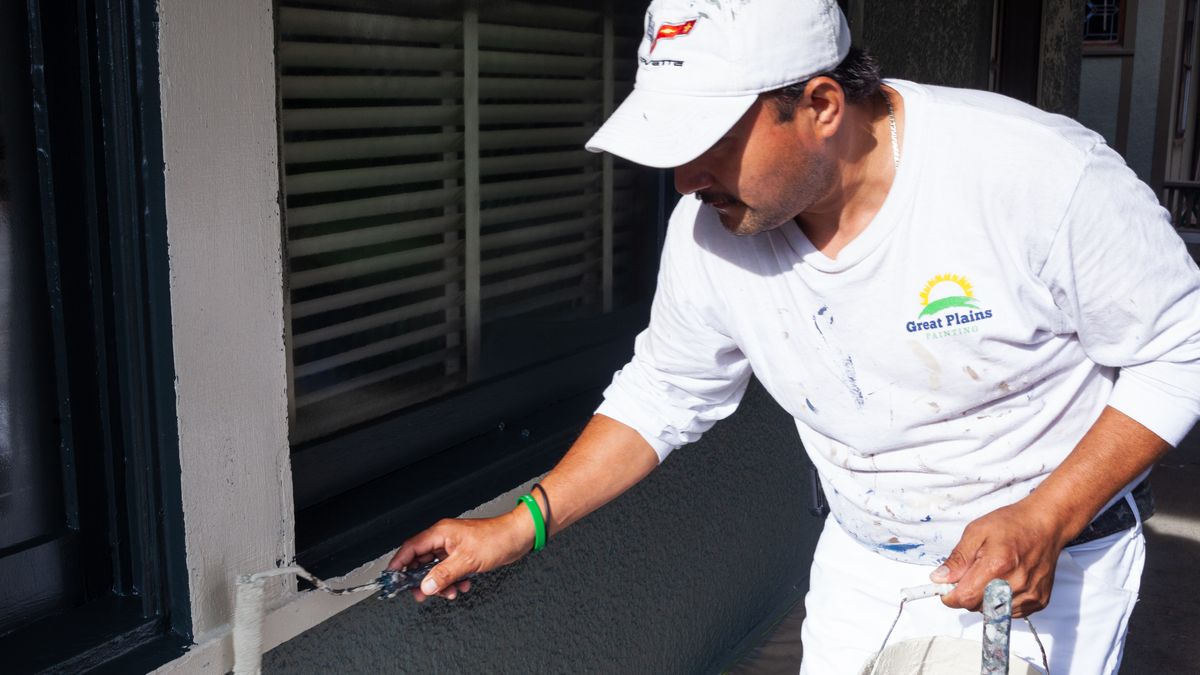 Painter with a mini roller painting exterior trim