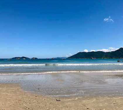 Vista da faixa de areia com mar azul ao fundo e céu sem nuvens