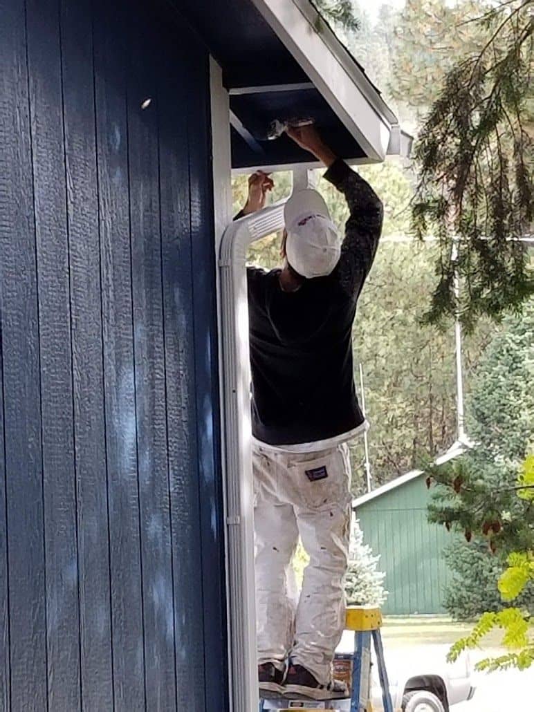 enlarged photo of man painting the exterior of a home dark blue