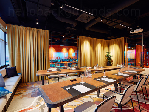 Modern boardroom with artistic flooring featuring curtained interior windows and V shaped table Zoom background