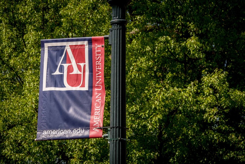 A campus flag hangs from a street light at American University